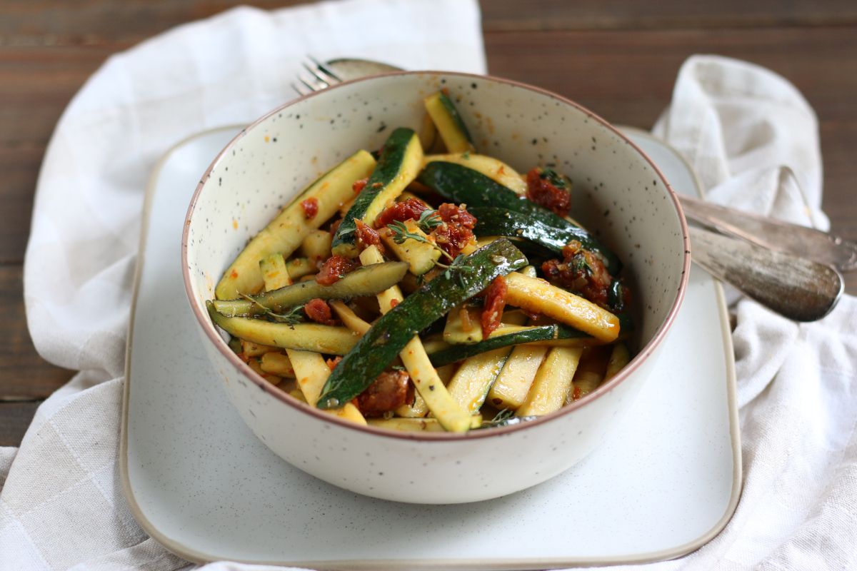 Lauwarmer Zucchini-Salat mit Dörrtomaten in einer Schale angerichtet